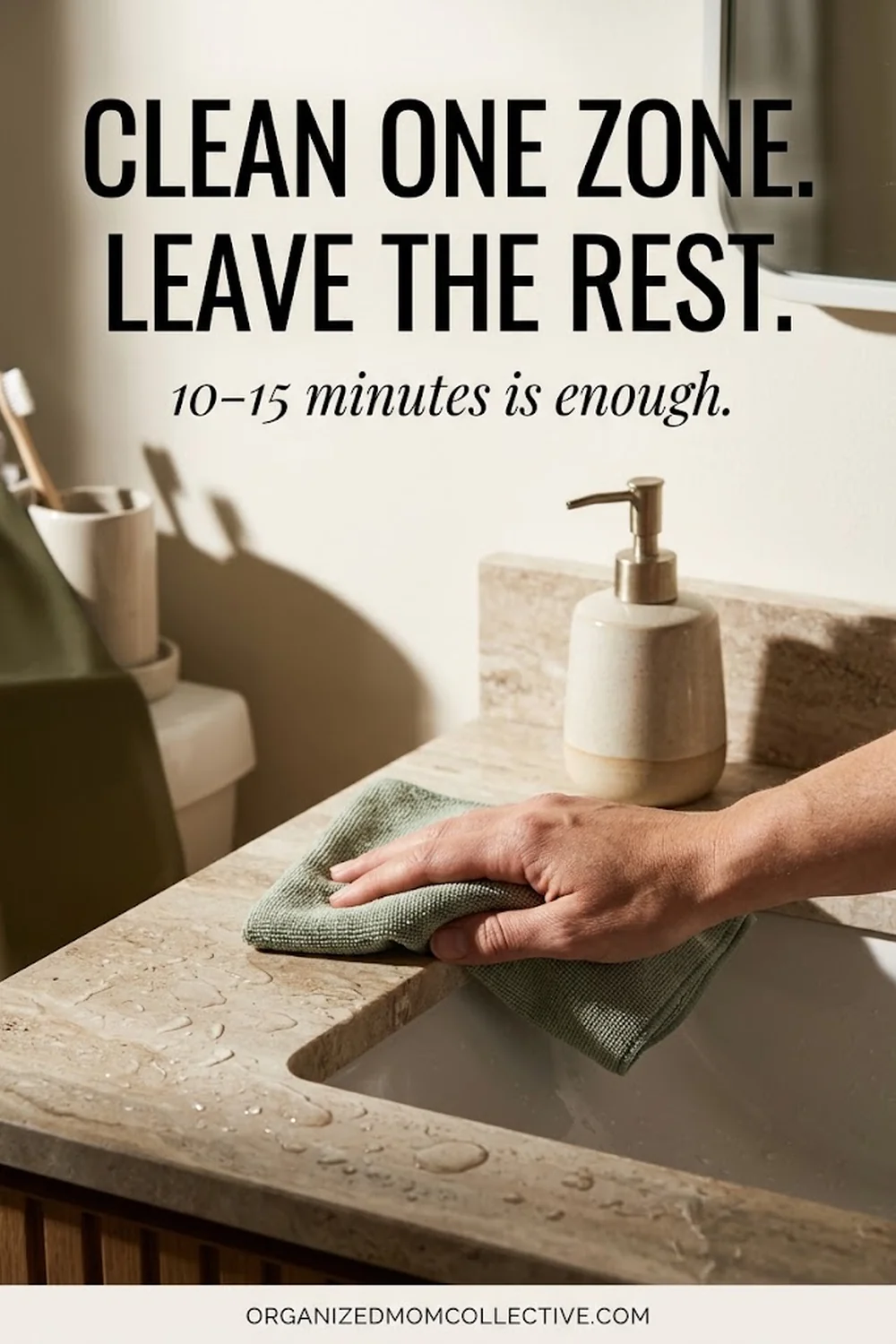 A hand wipes a stone bathroom counter with a sage cloth beside a ceramic soap pump, with the headline “Clean one zone. Leave the rest.” and the line “10–15 minutes is enough.”