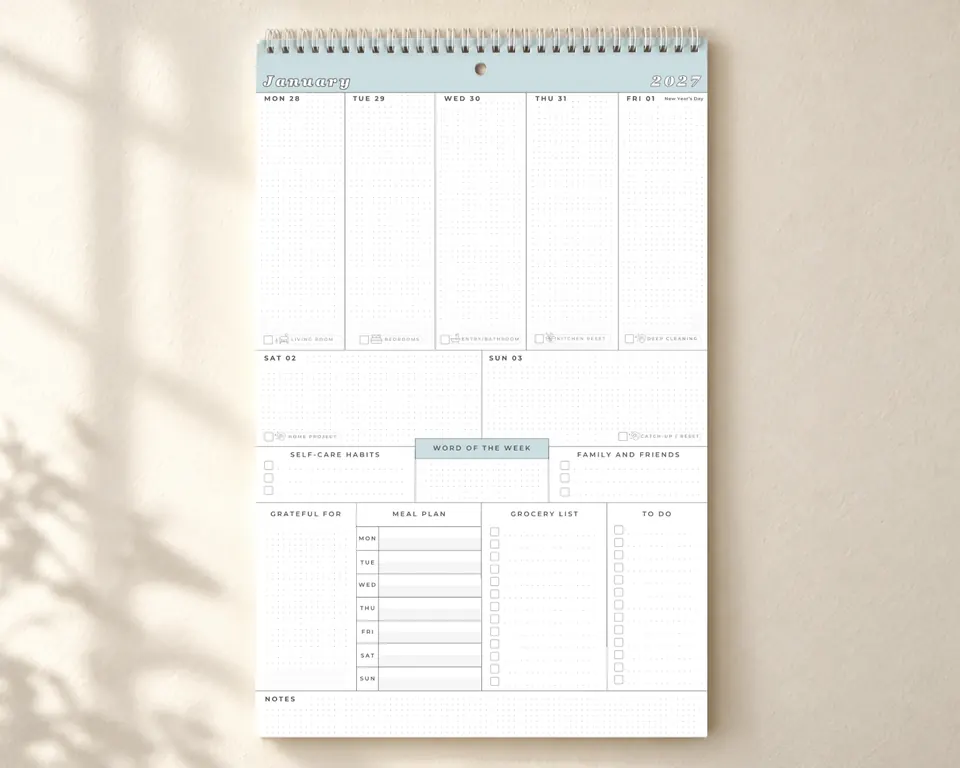 The calendar hanging on a wall from its spiral binding, open to the first week of January 2027, before anything is written in.
